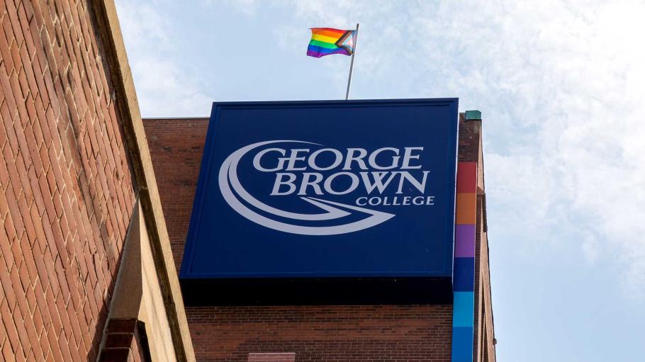 Pride Flag flying over George Brown College sign at 200 King Street East.