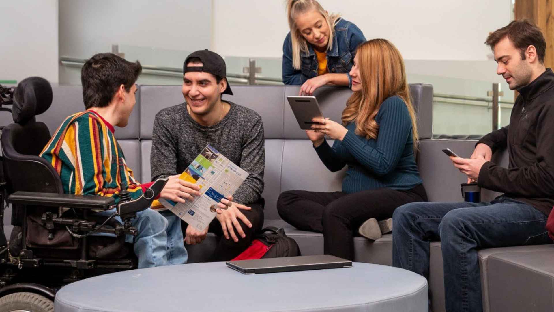 Students gather on or around couches, in different conversations with one another.