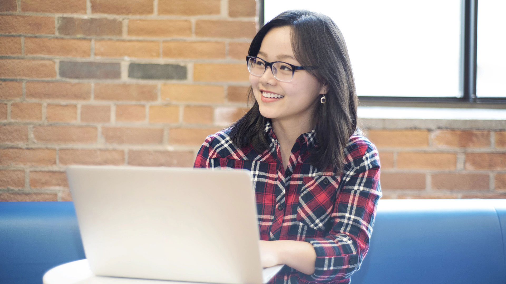 a female asian student looking up from her laptop smiling