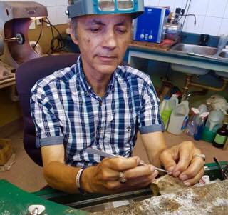 Lui Ferritto working on jewellery at a desk. 