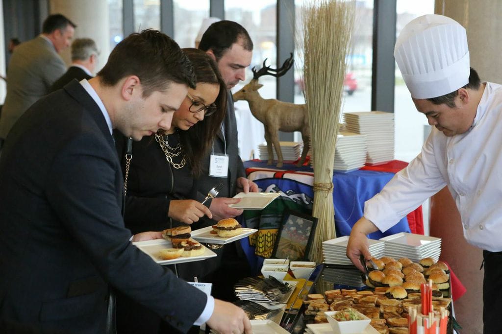 People choosing food at a buffet table with a chef arranging food