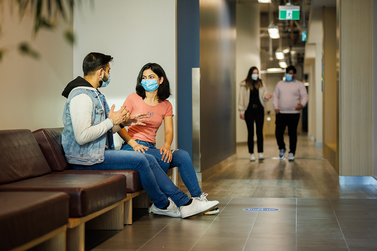 students talking on bench in hallway at Waterfront Campus
