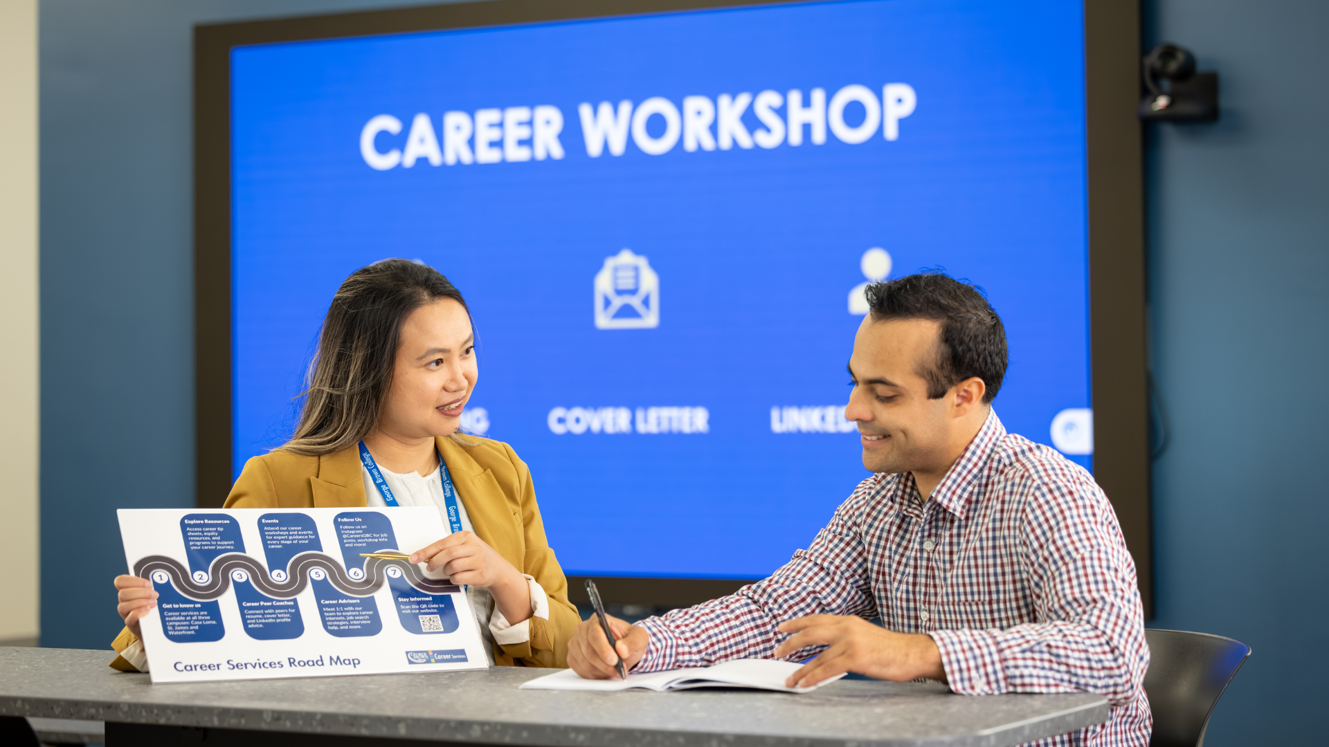 An advisor instructs a participant in a career workshop, pointing to a graph.