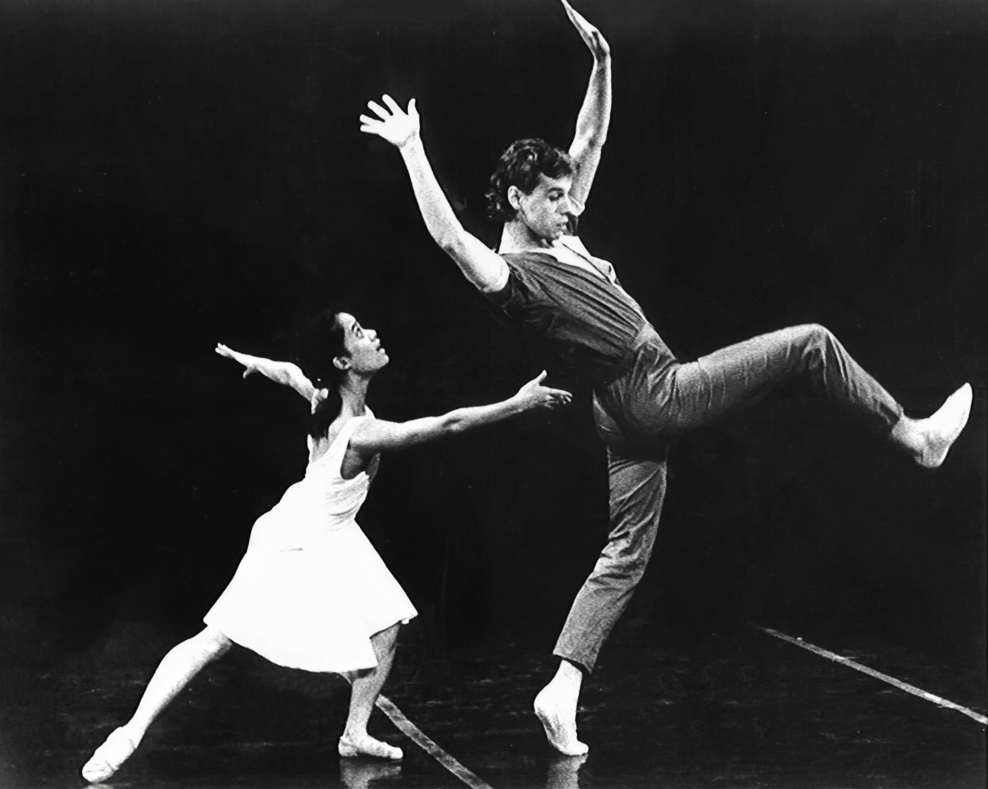 Bengt Jorgen in a stage production dances dramatically with arms outstretched while a ballerina in white crouches behind him