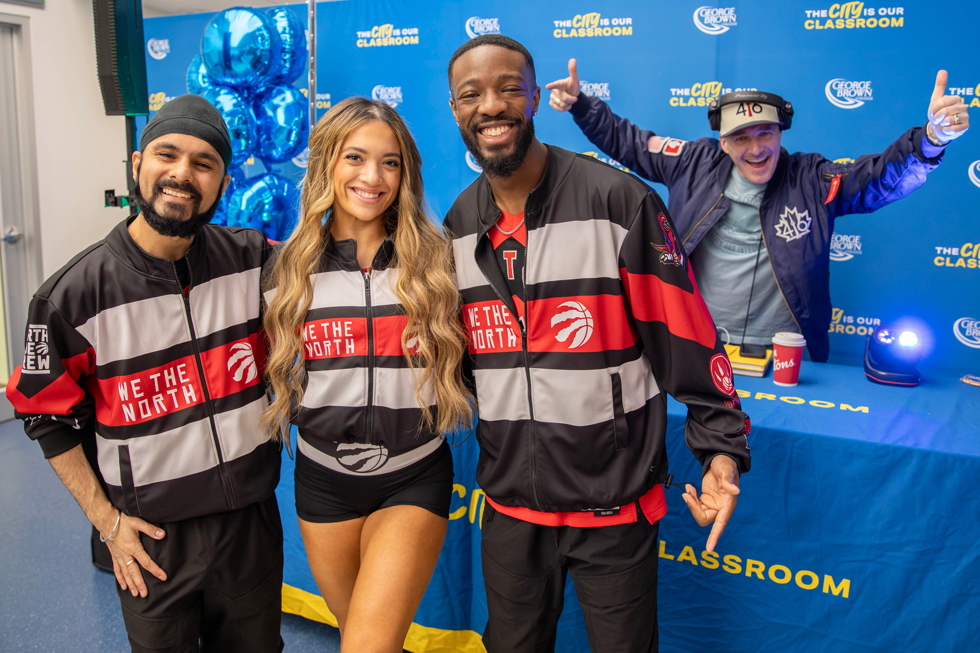 Raptors dancers smile in front of the DJ at the open house