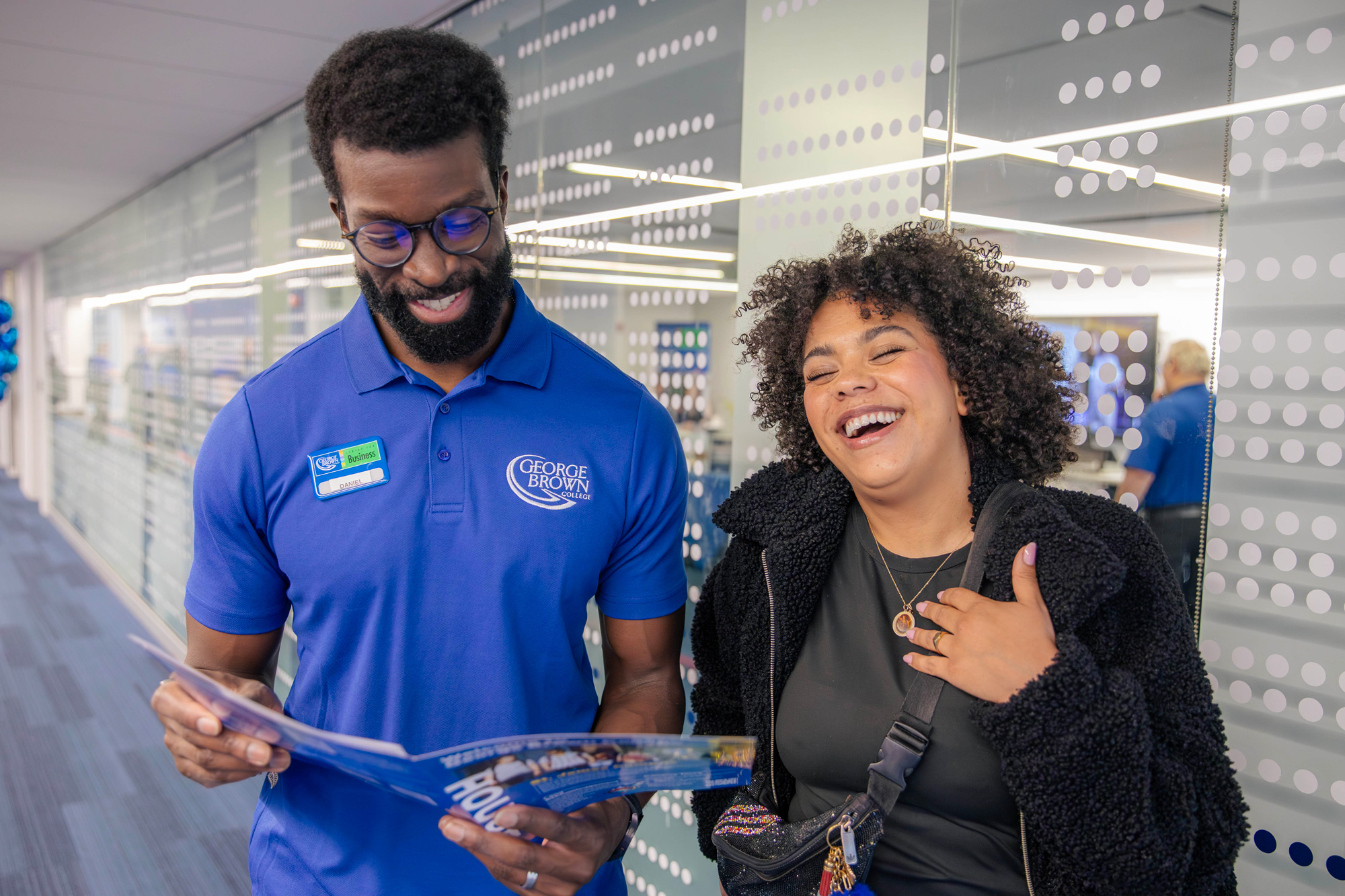 A studnet at the open house laughs with a staff member at the open house