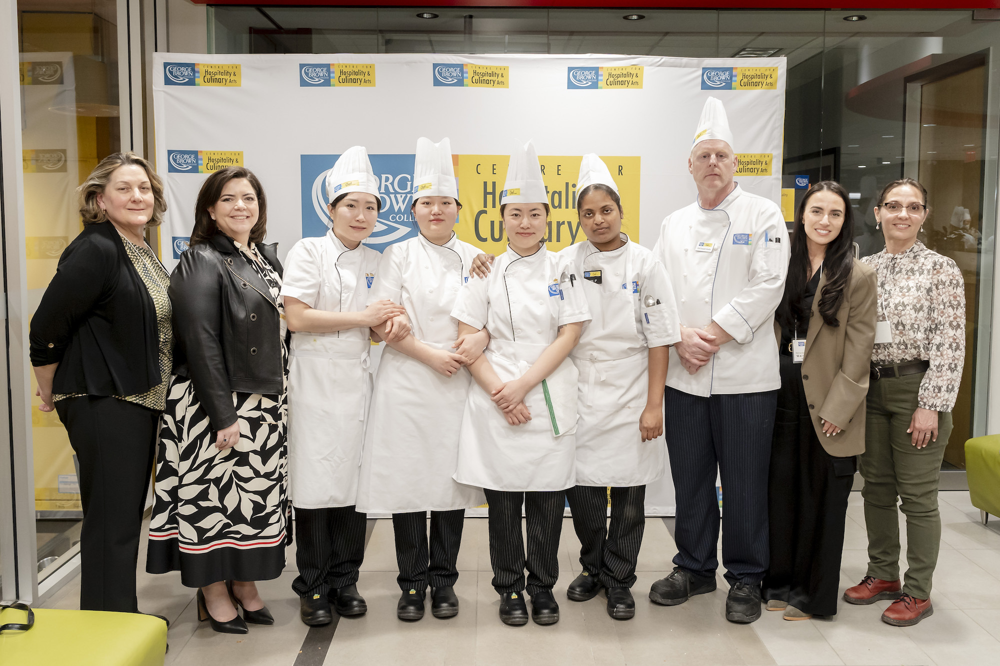 Student chefs and faculty pose together at the Room 4 Desserts event