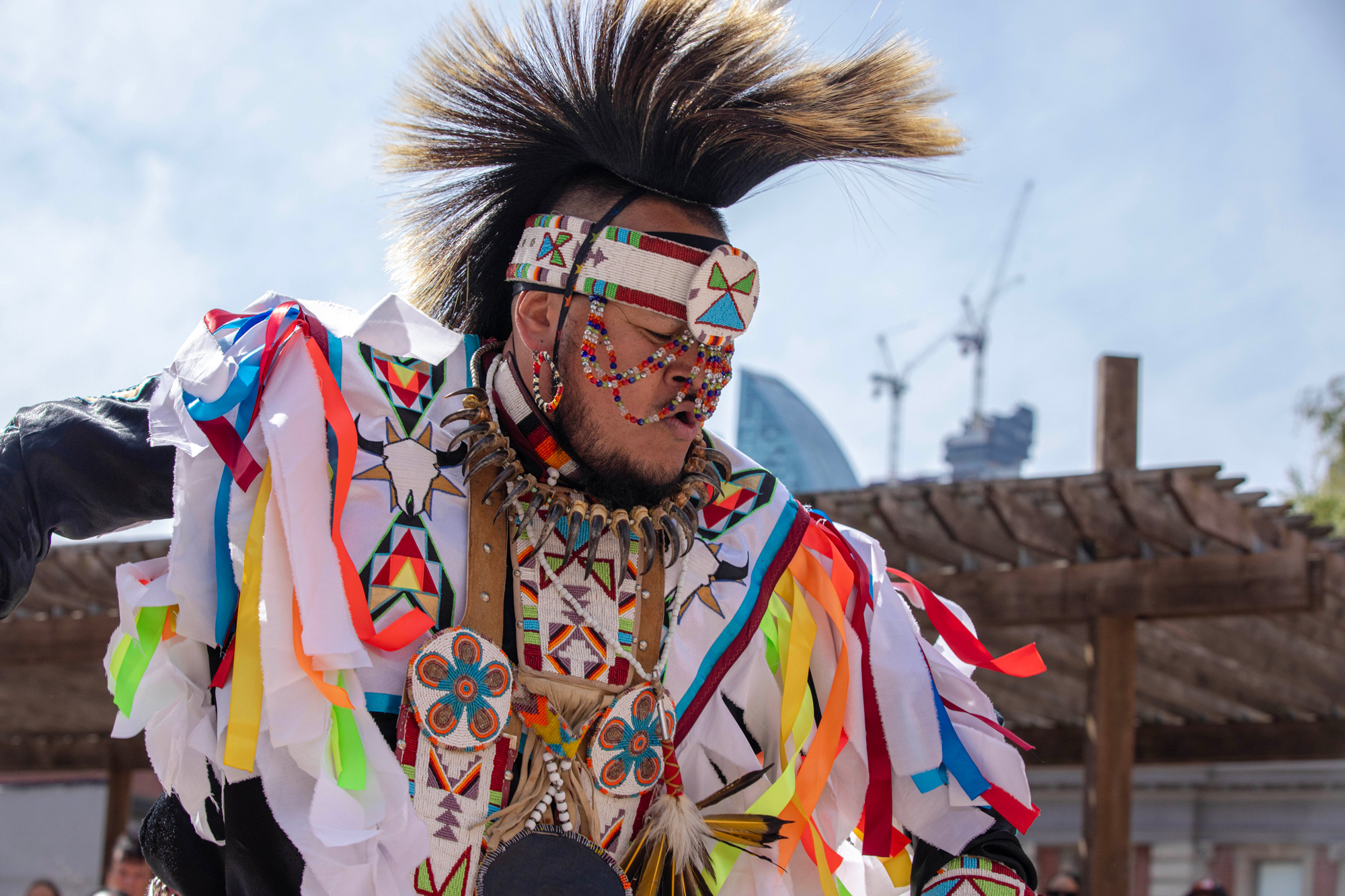 An indigenous person dances in traditional clothing and decoration
