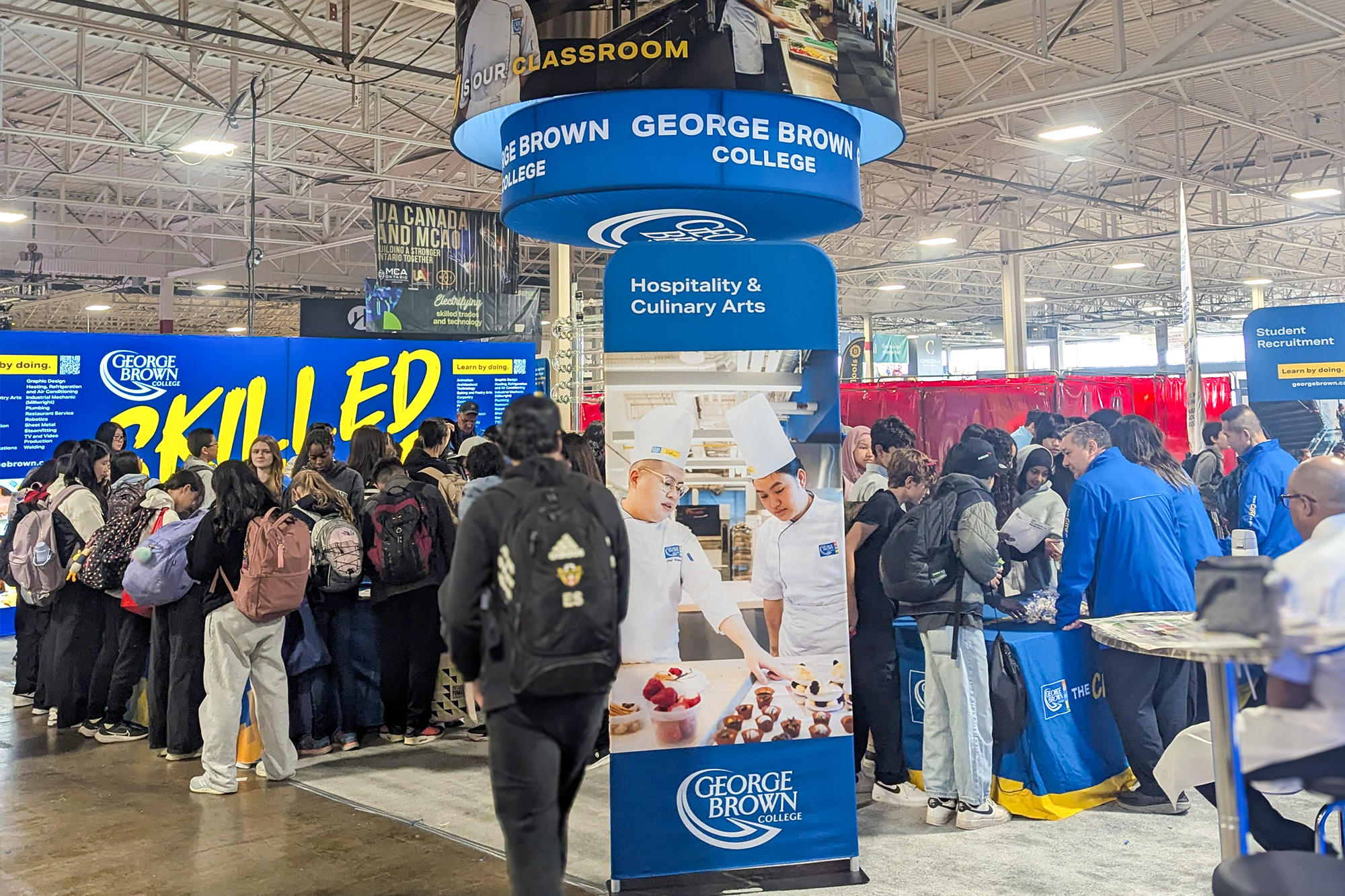 A bright blue and yellow competition booth with many young students exploring