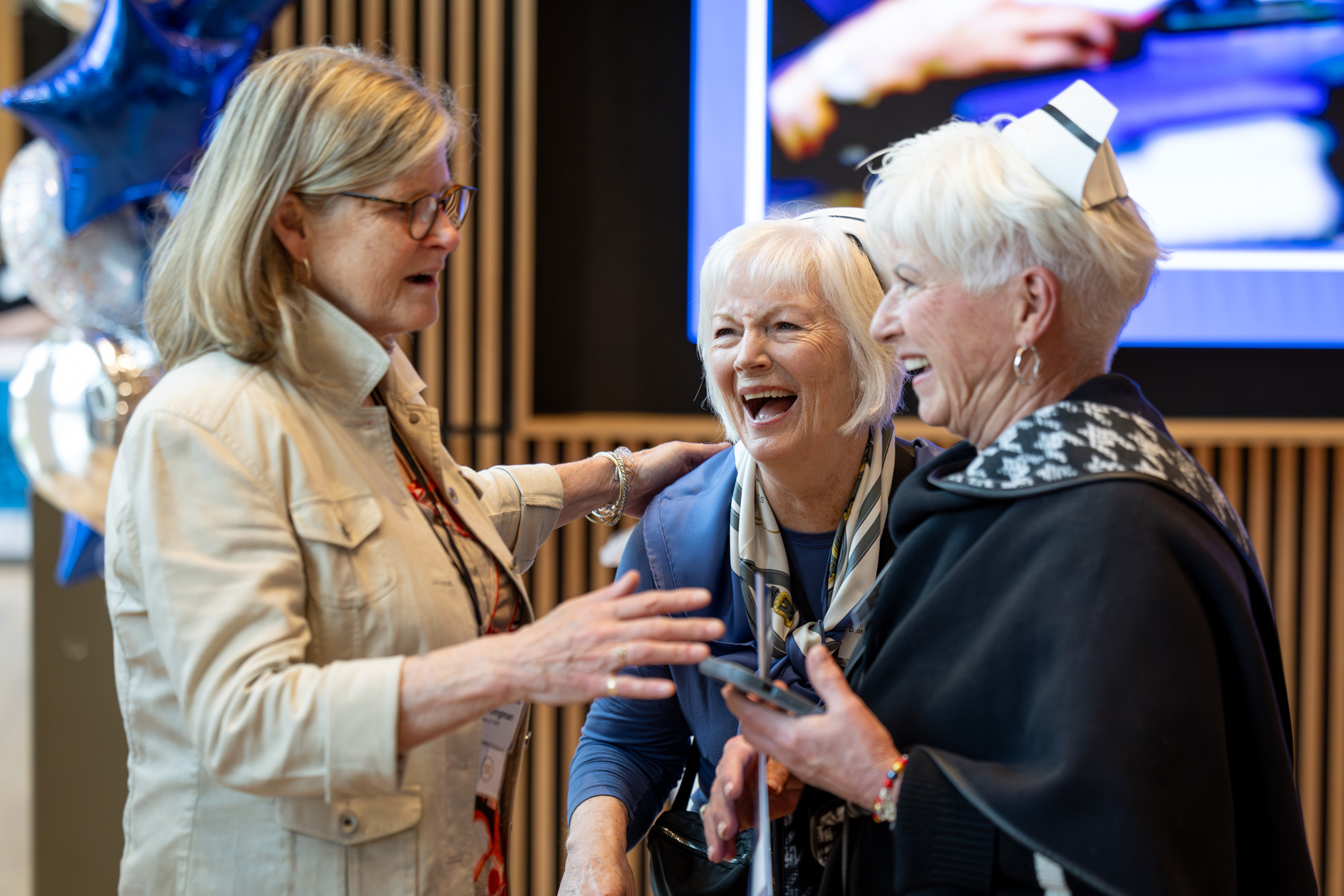 Three alumni nurses chat and laugh together at the 50th nursing reunion at George Brown College