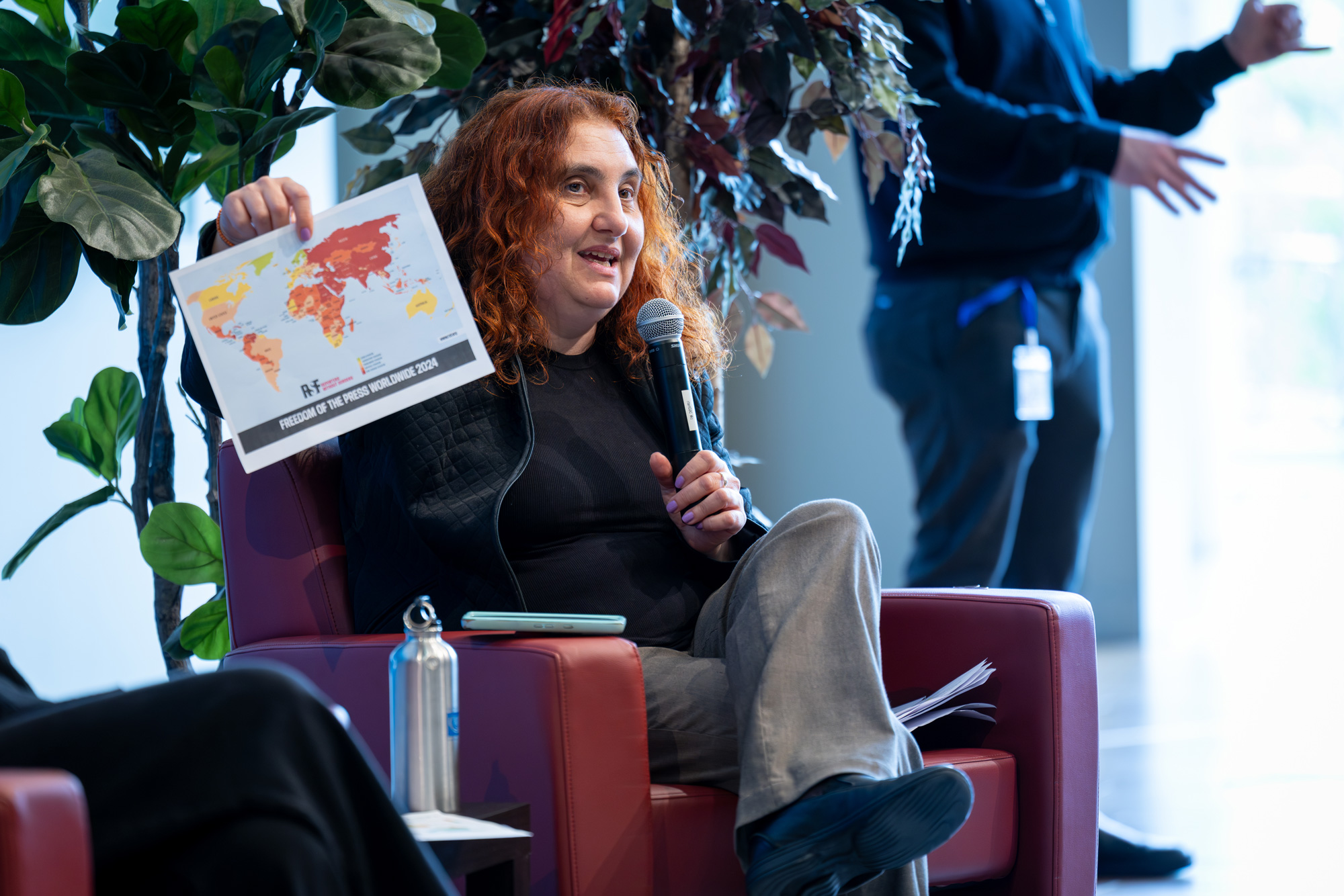 A panelist with a microphone holds up a map and speaks to the audience at the Pen Writer event