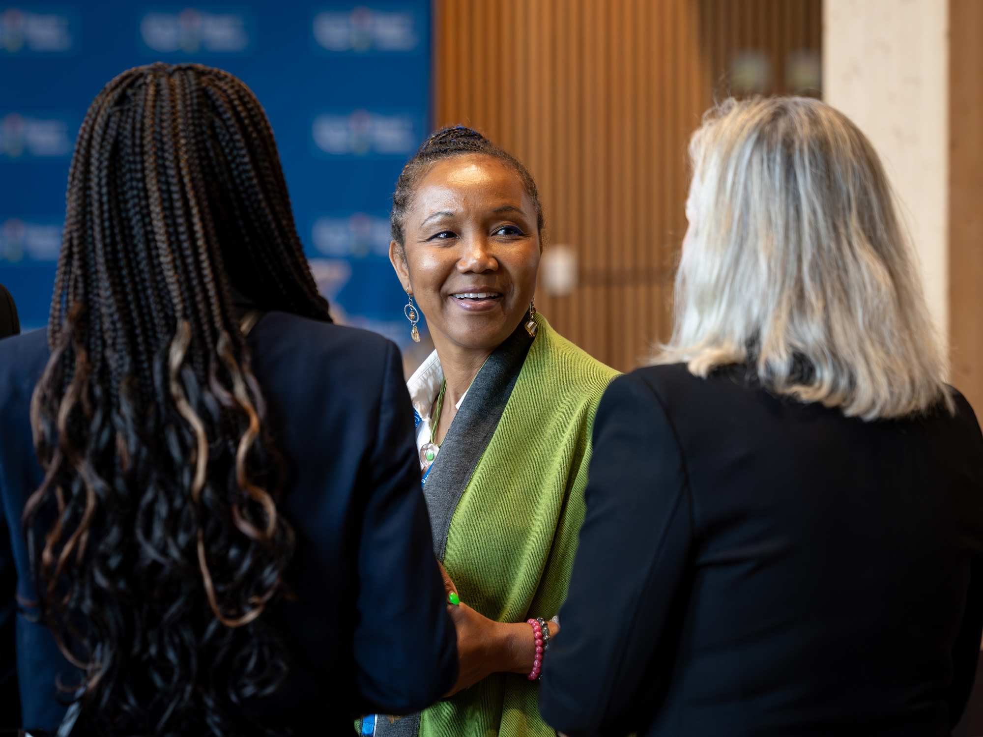 Three women chat and smile at the Mitchell Cohen book talk