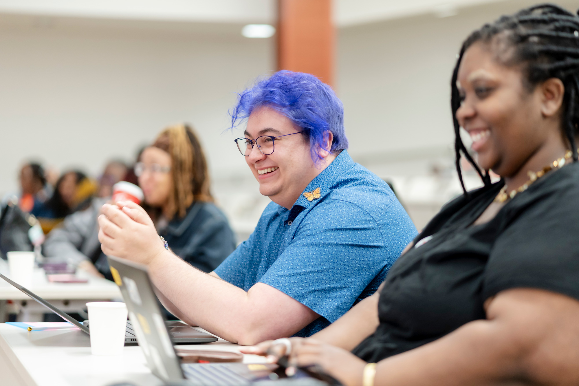 Two seated guests at the Black Chat and Chill event smile as they listen to the speaker