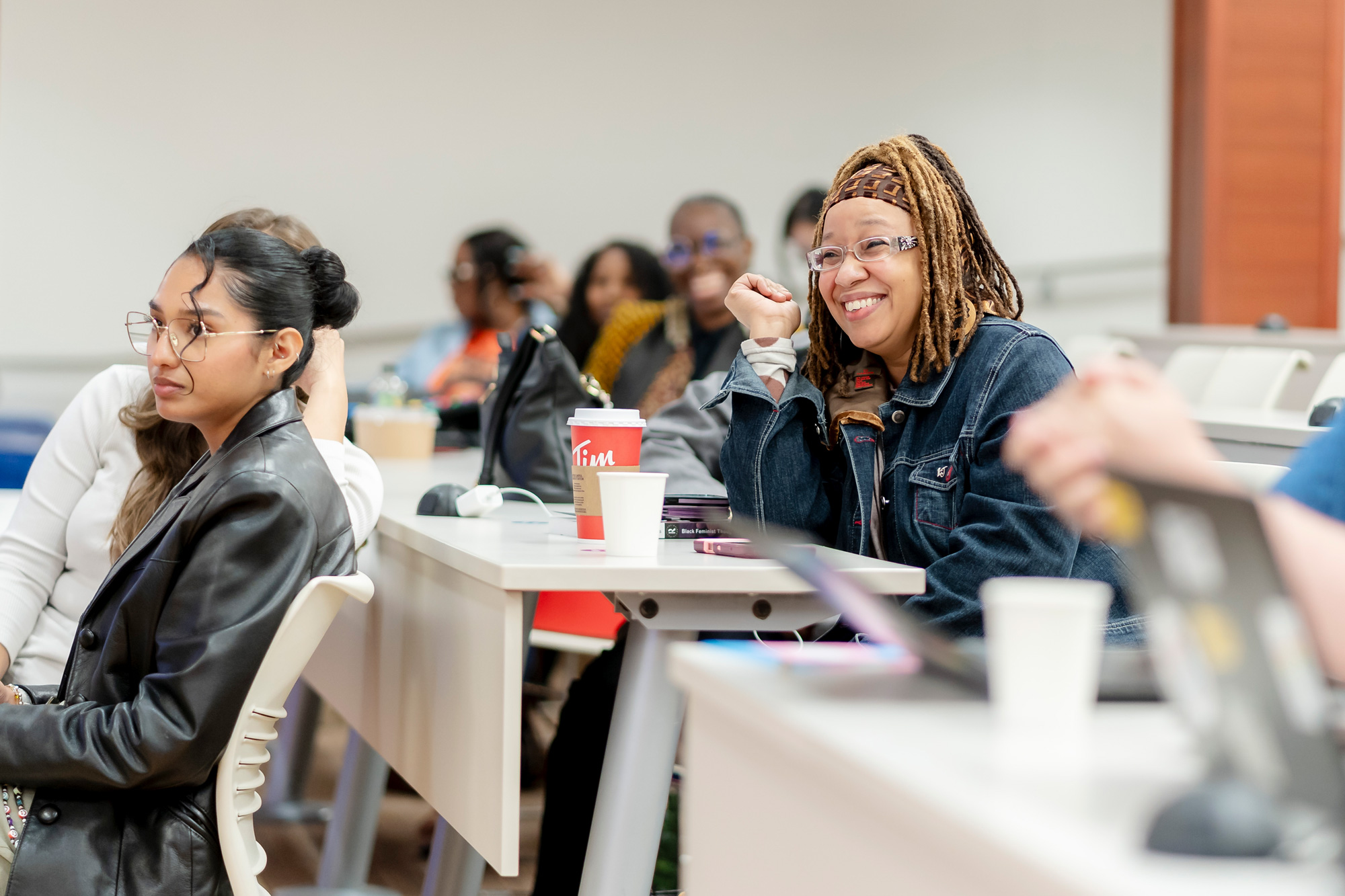 Seated guests at the Black Chat and Chill event smile as they listen to panelists