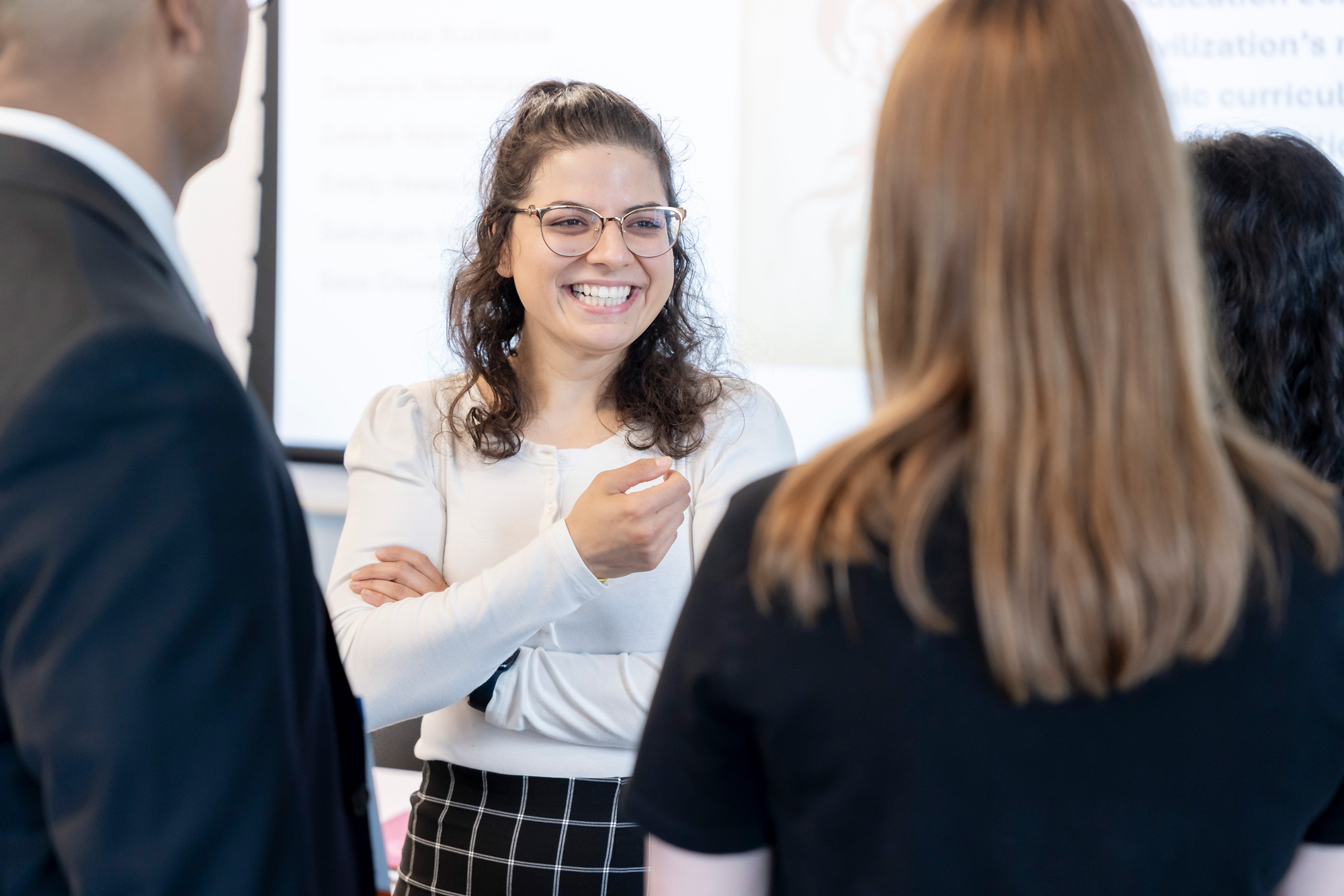 A women in glasses and white top chats with a group at Congress