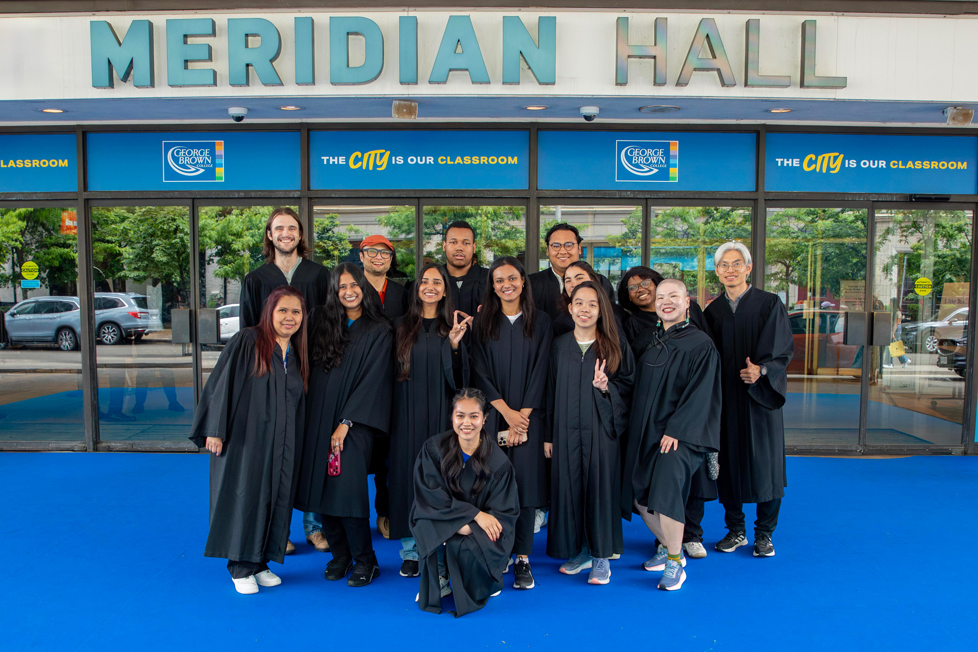 Convocation staff and volunteers pose on a blue carpet outside of Meridian Hall