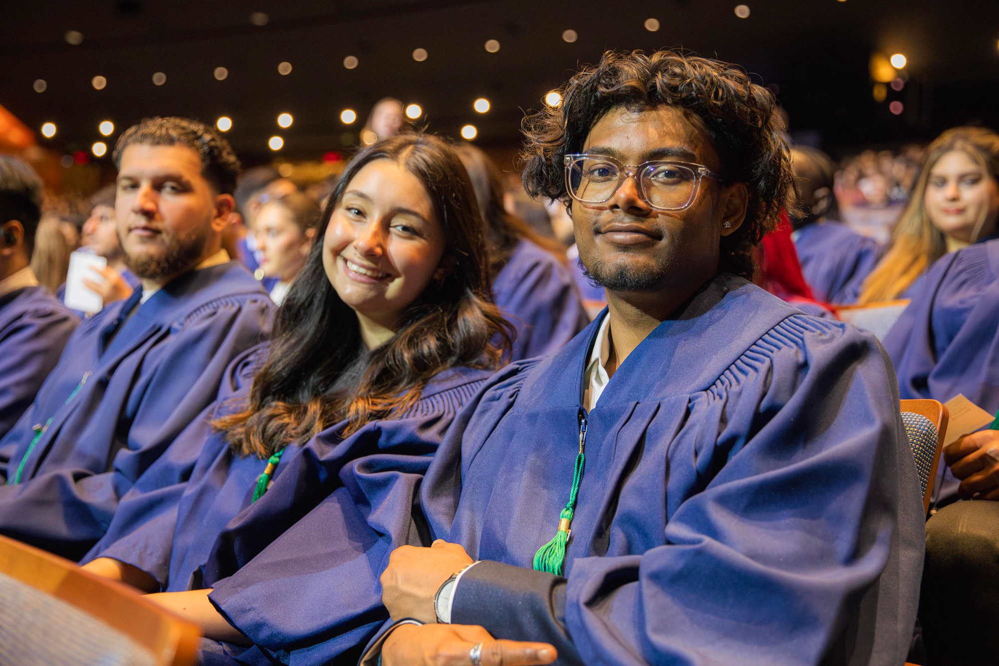 A row of students in the graduation gowns are seated in the auditorium