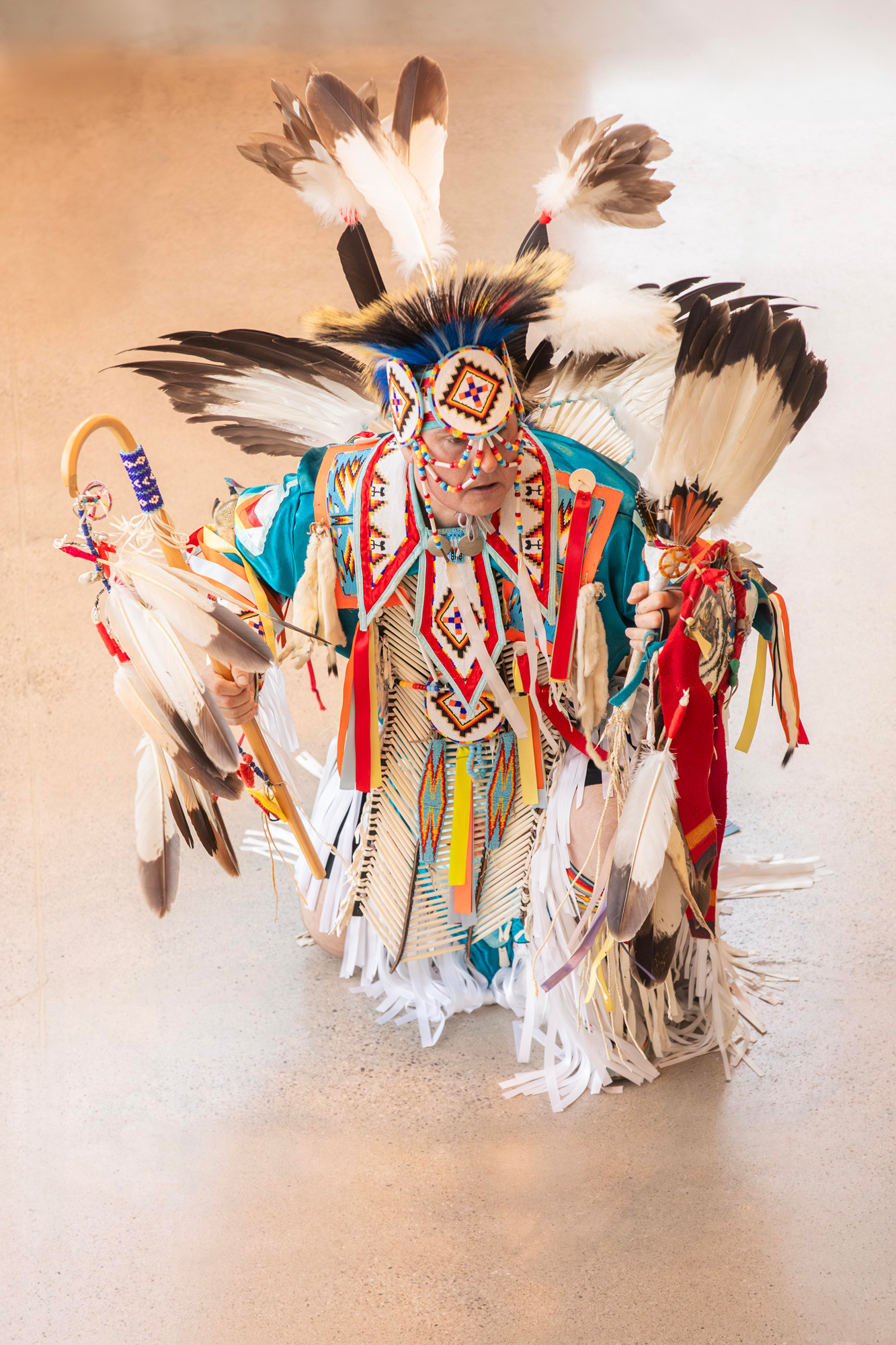 A man in full traditional Indigenous clothing performs at George Brown College's Limberlost Place