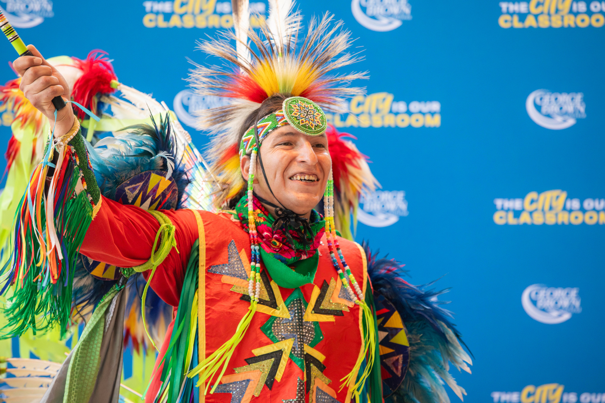 A man in traditional Indigenous clothing smiles after dancing at Limberlost Place
