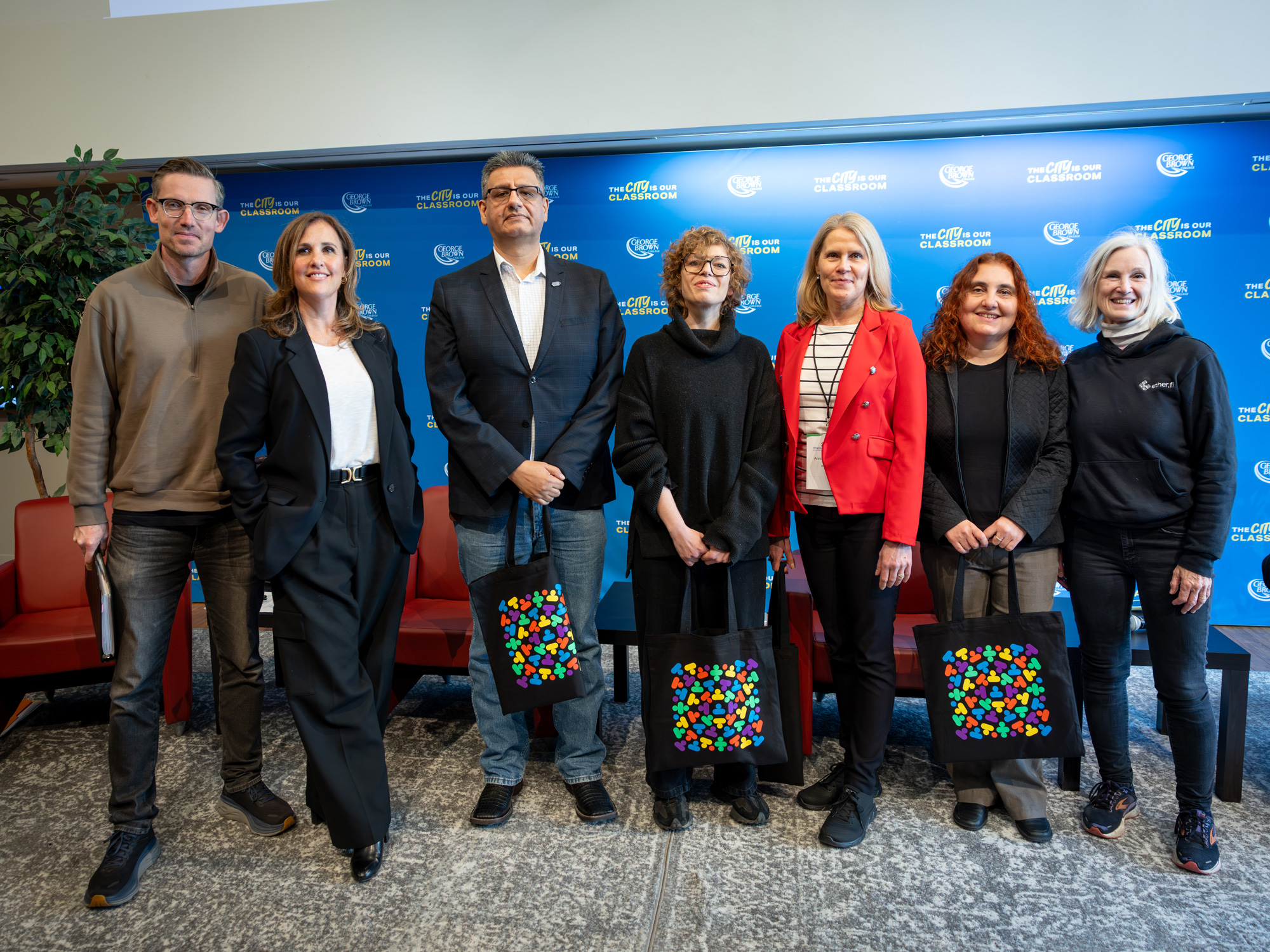 A group of seven panelists from the Pen writer in residence panel pose together holding Congress tote bags