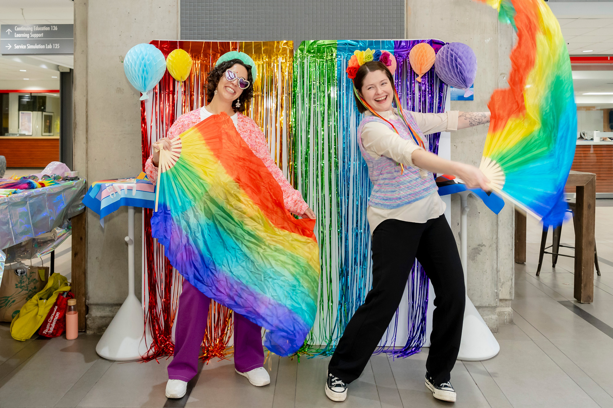 Two people laugh joyfully as they wave rainbow flags