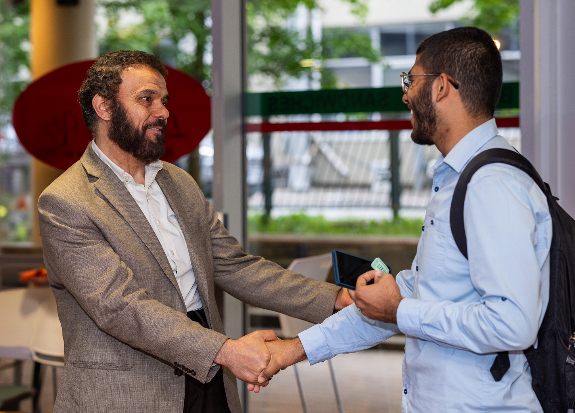 Dean Adel Essayed shakes hands with an alumni