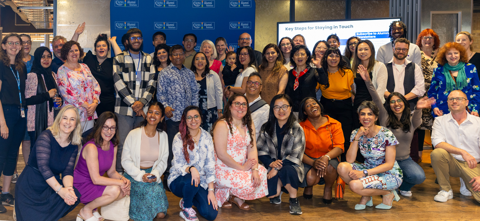 A large group of alumni, new grads, staff and faculty pose for a photograph at the summer alumni social events at Casa Loma campus