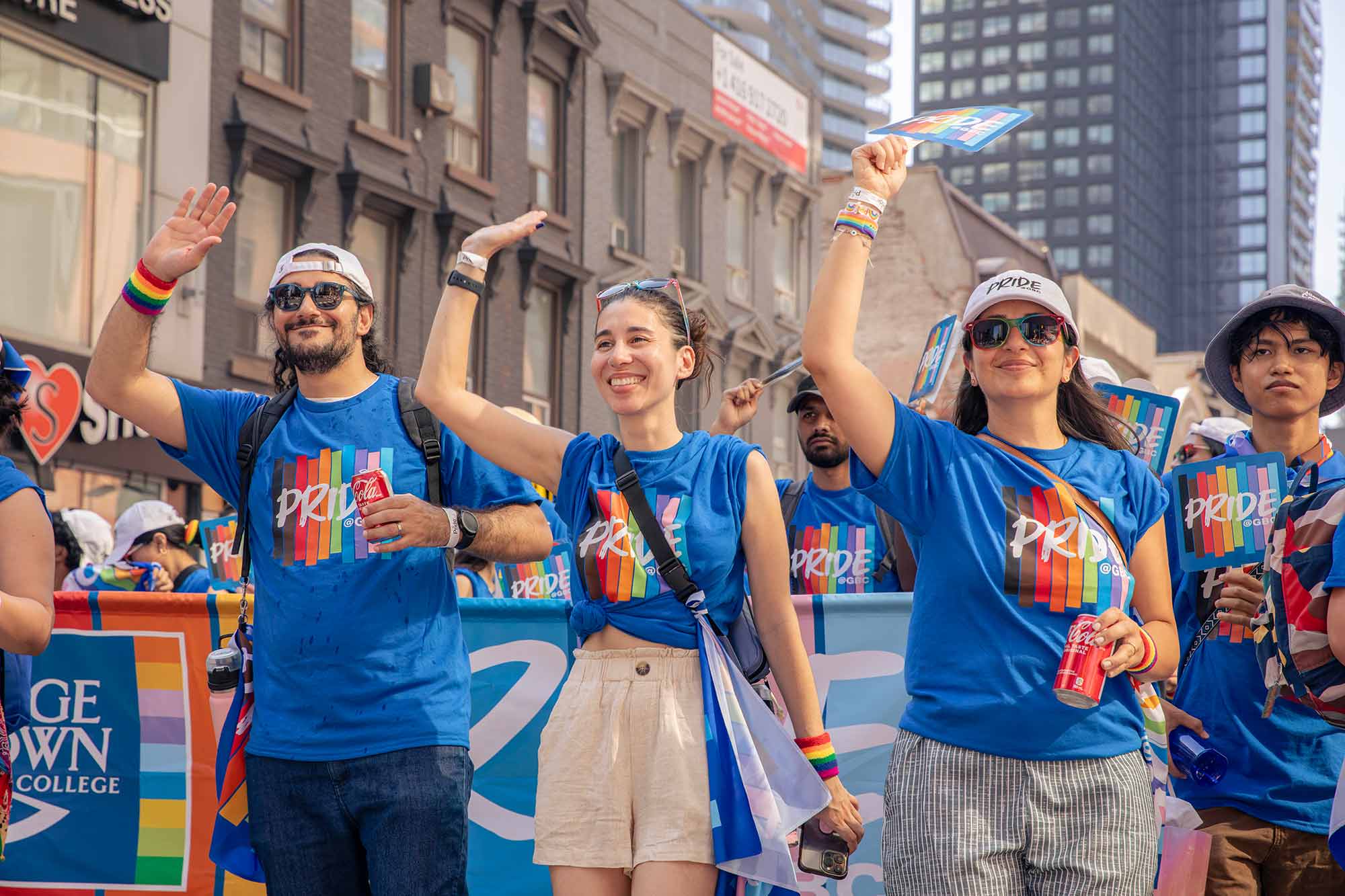 Four Pride parade marchers waving