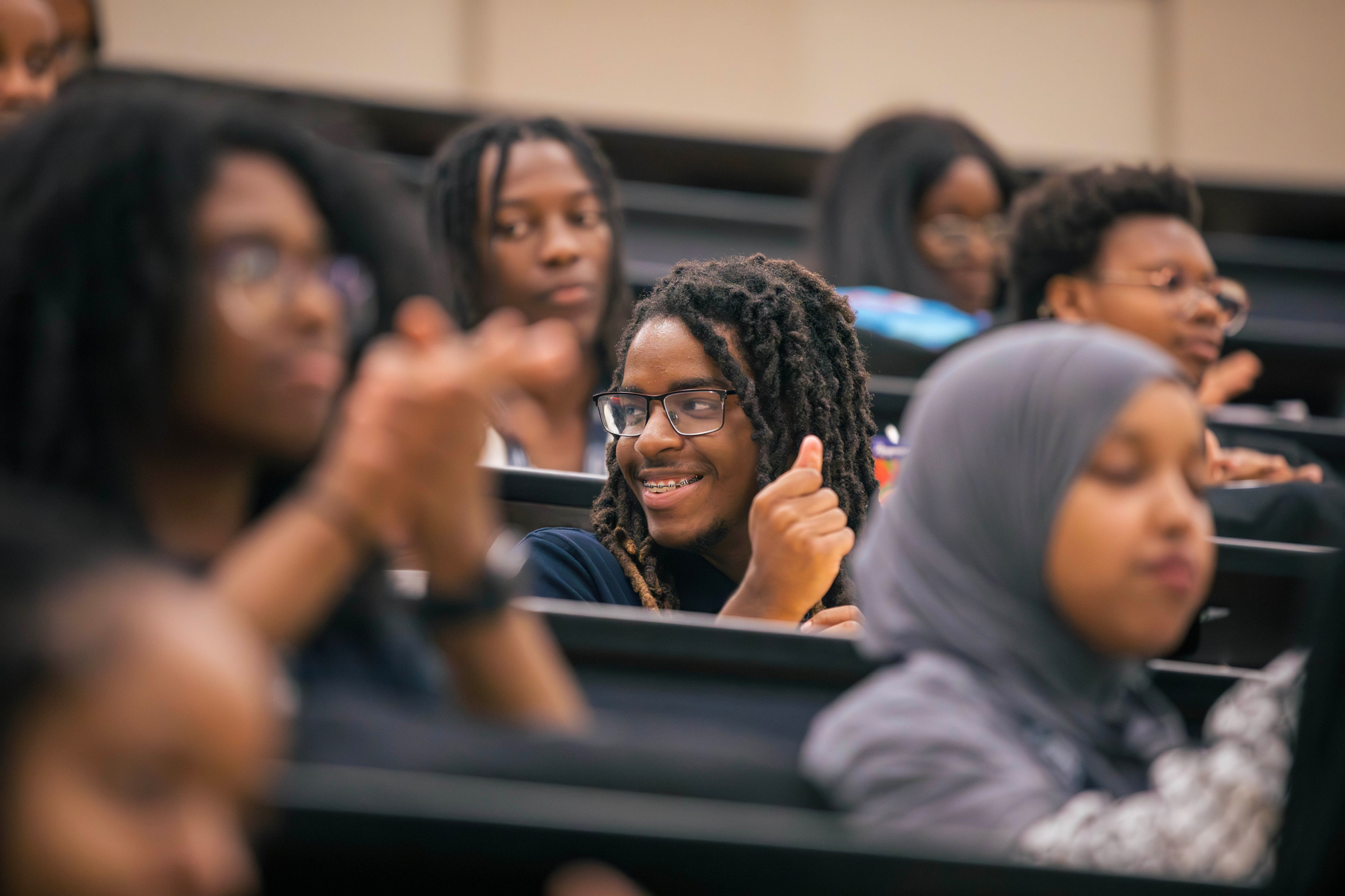 Seated students clap for a speaker in the auditorium at the Black student summer leadership symposium