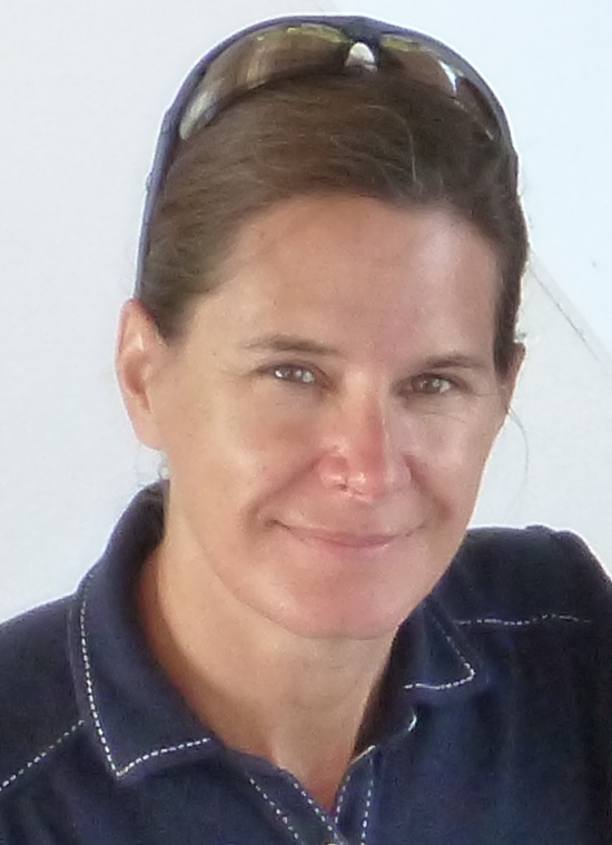 A woman with brown hair and a jean shirt, smiling