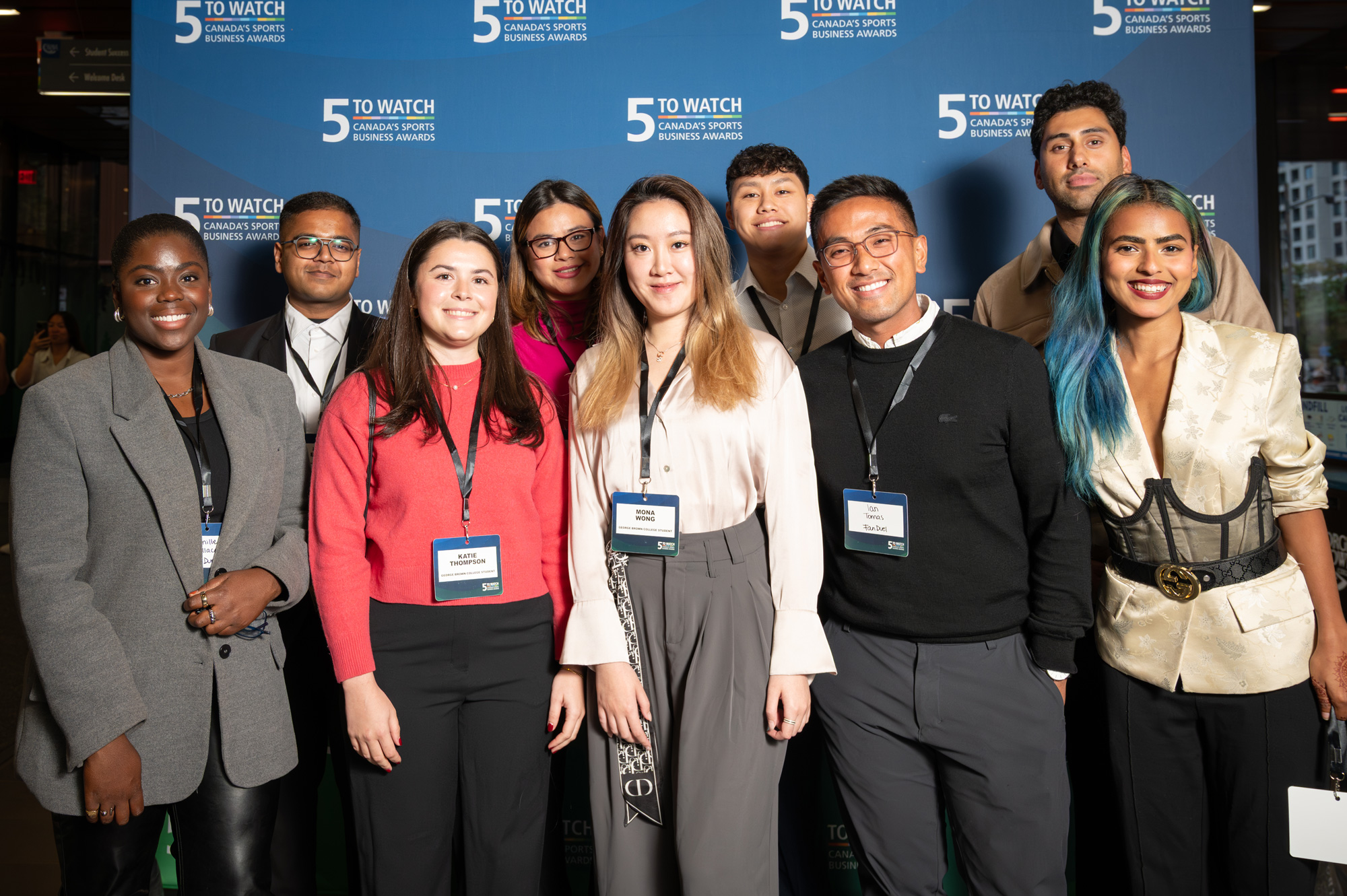 Student award recipients of the 5 to Watch awards pose together in front of a blue background