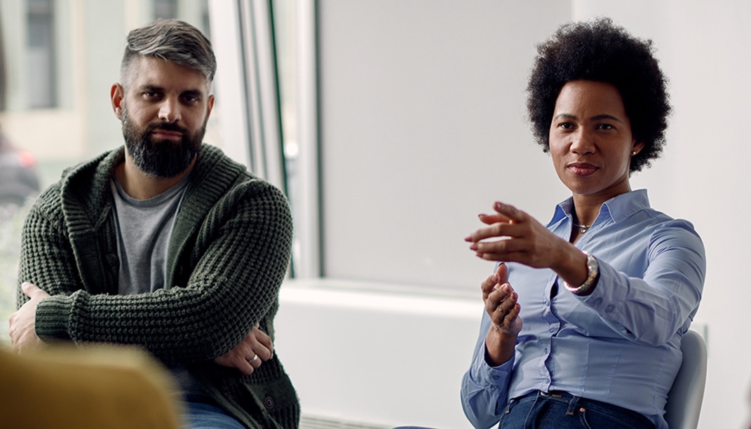 Two people talking as part of a larger circle in a meeting.