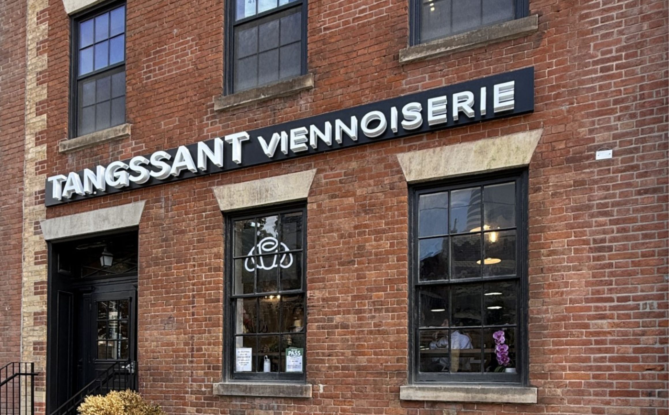 A photo of a pastry shop Tangssant Viennoiserie sign on front of brick building