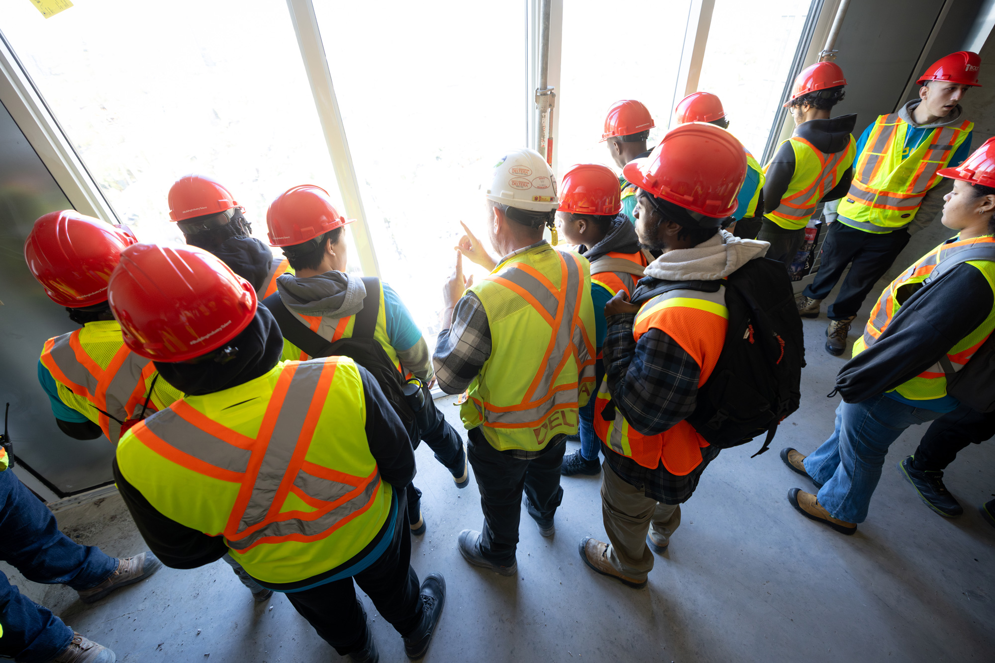 Students on a construction site look out the unfinished windows over the city