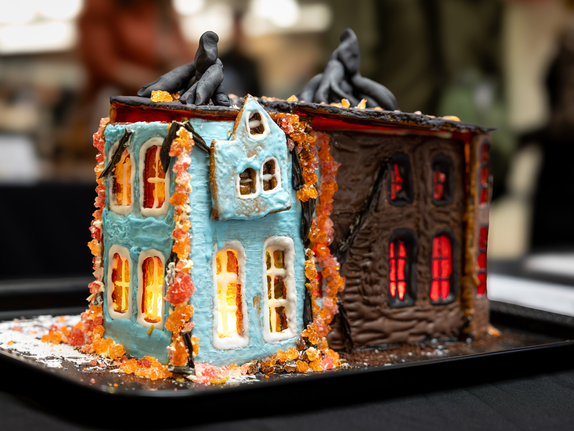 A gingerbread house that is light blue on one side and dark brown with red lights on the other depicting a scene from Stranger Things