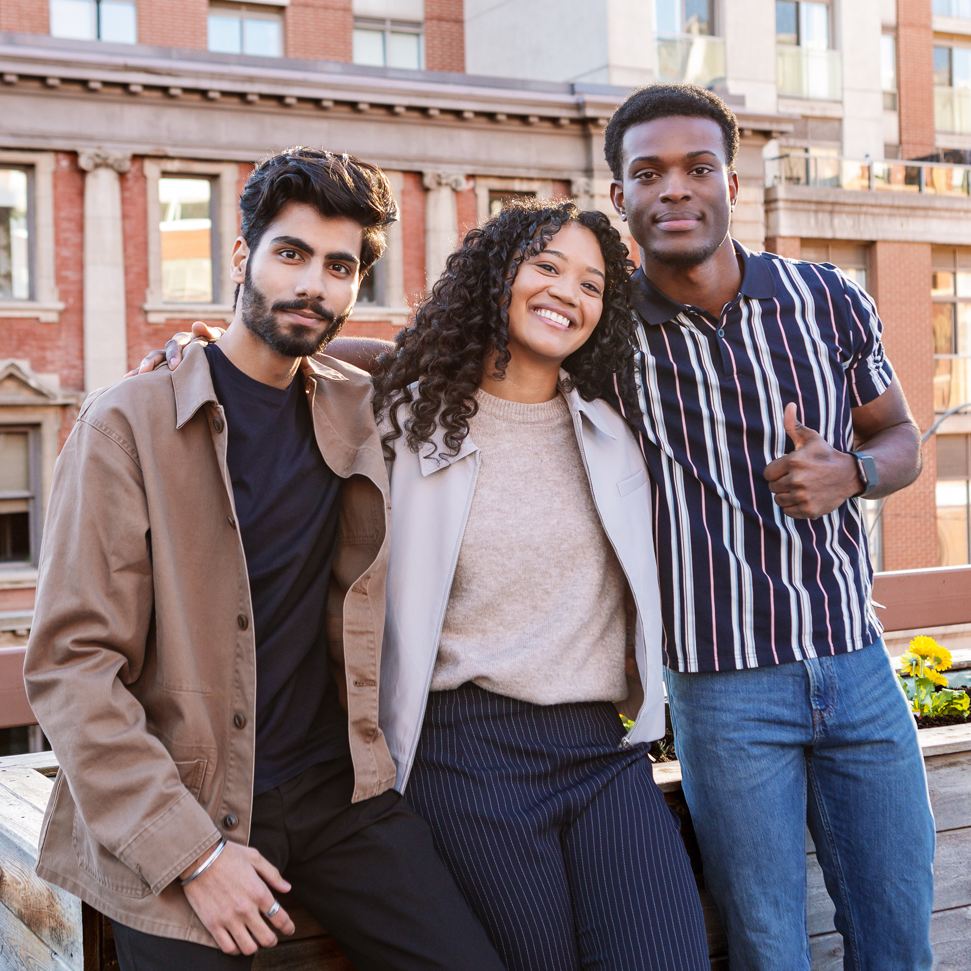 Three students hug outdoors on the St. James campus patio