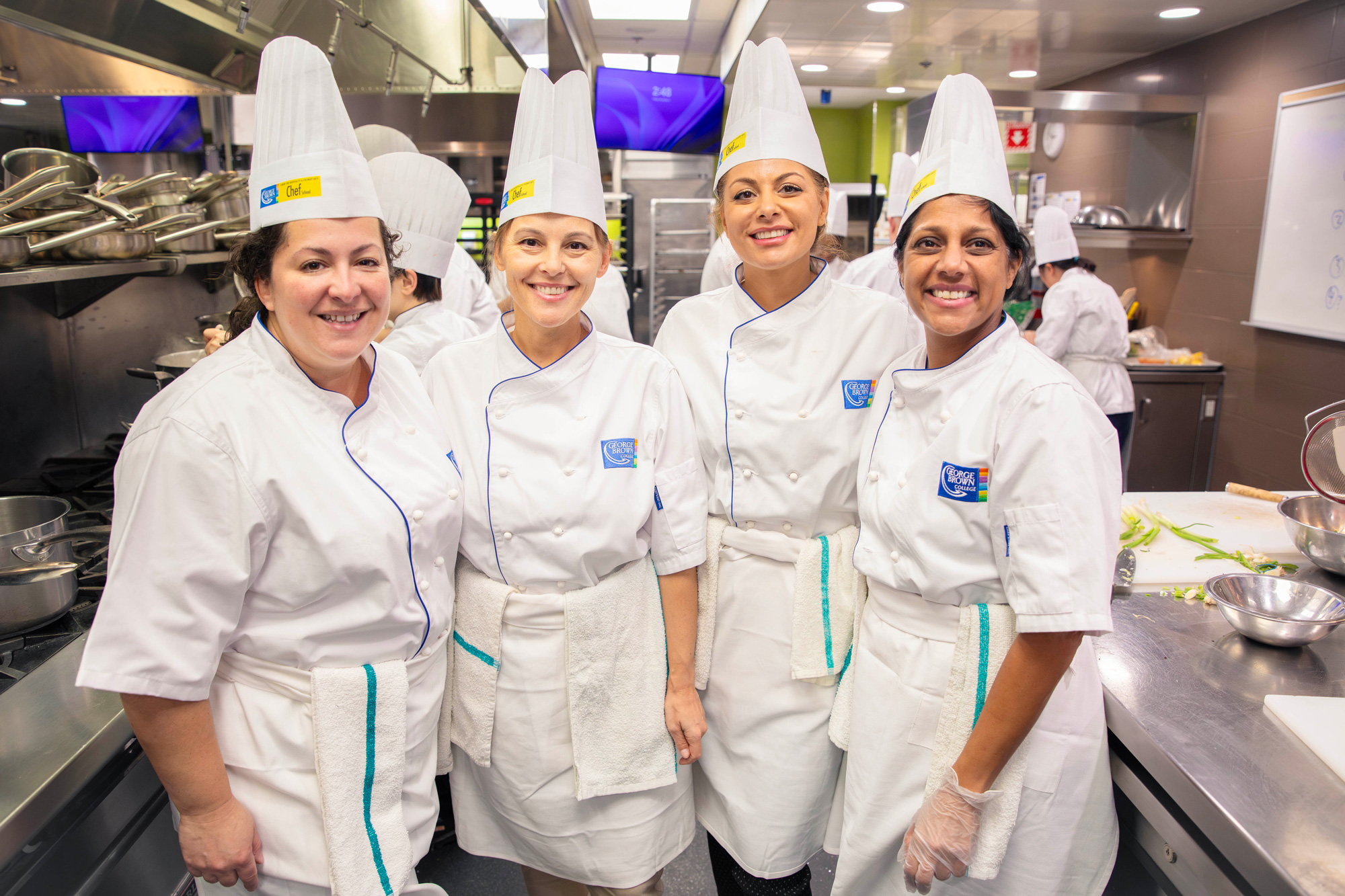 College leaders pose together in the Chef School kitchens as they prepare holiday meals