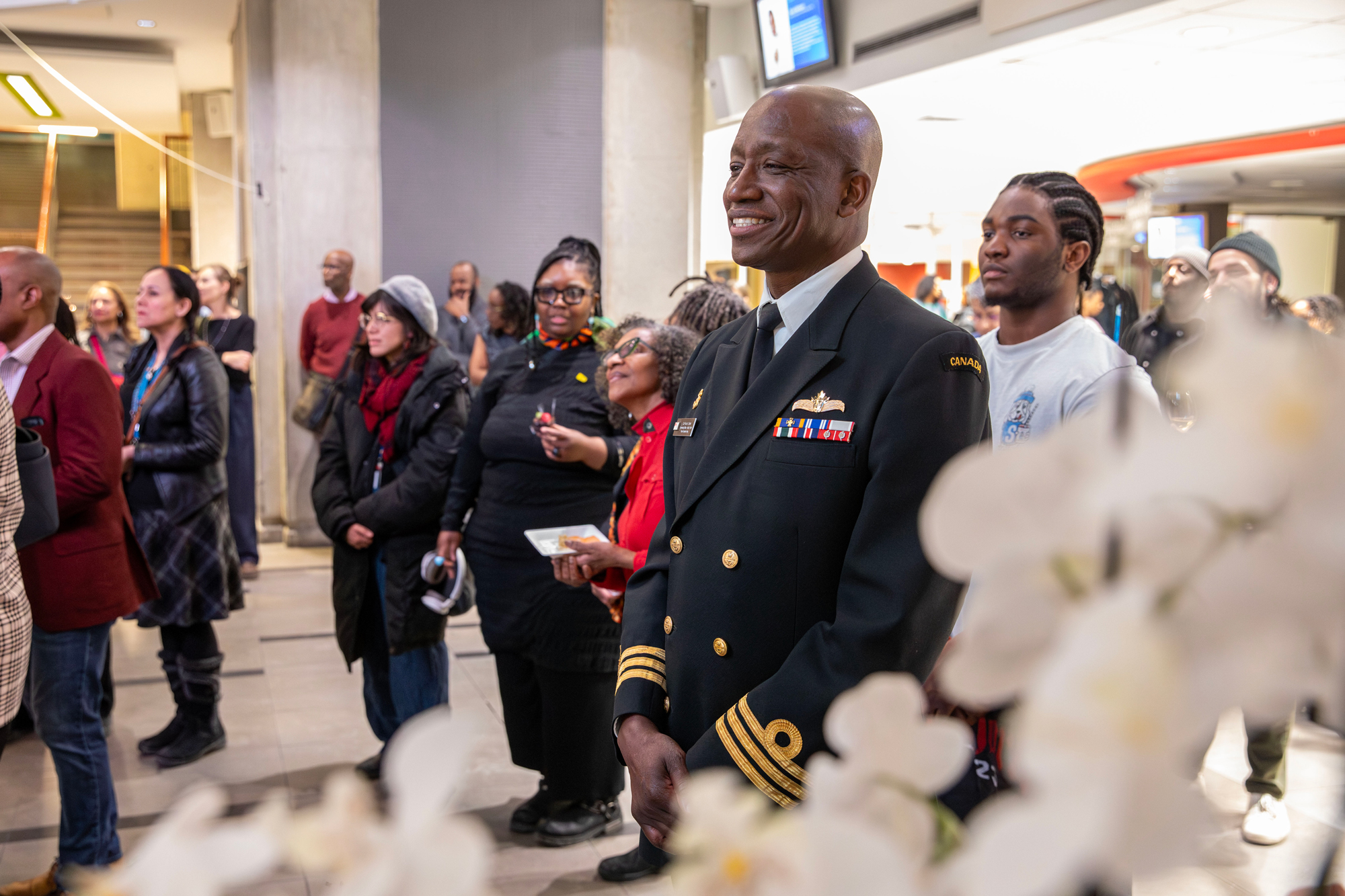 A man in uniform listens to the speaker as the Hubbard Atrium naming event