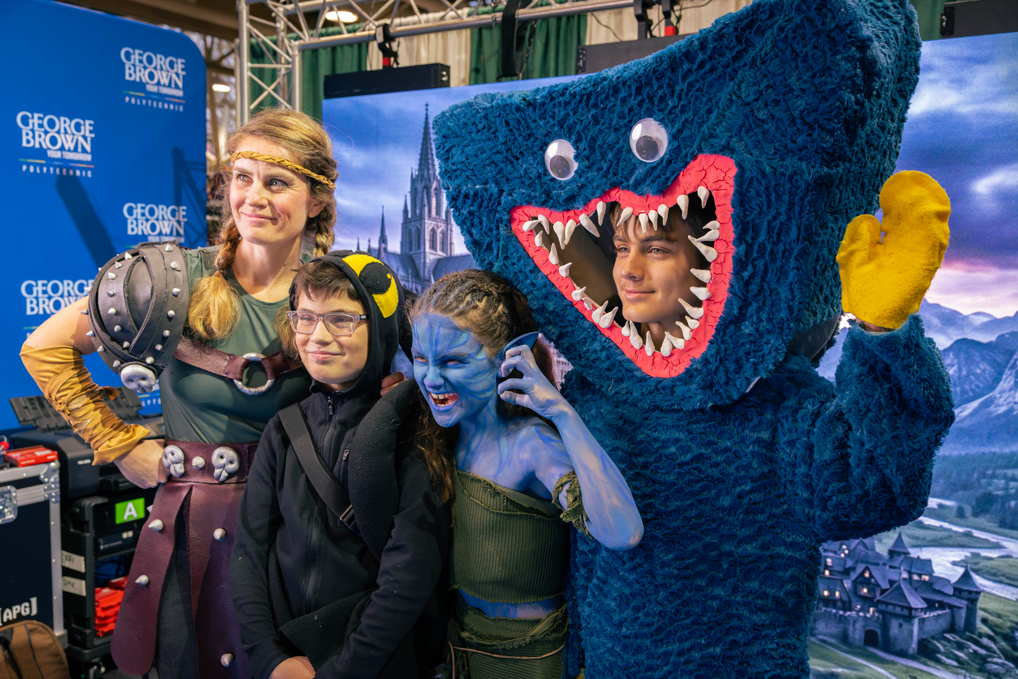 A family in costume pose in front of the LED wall at Comicon