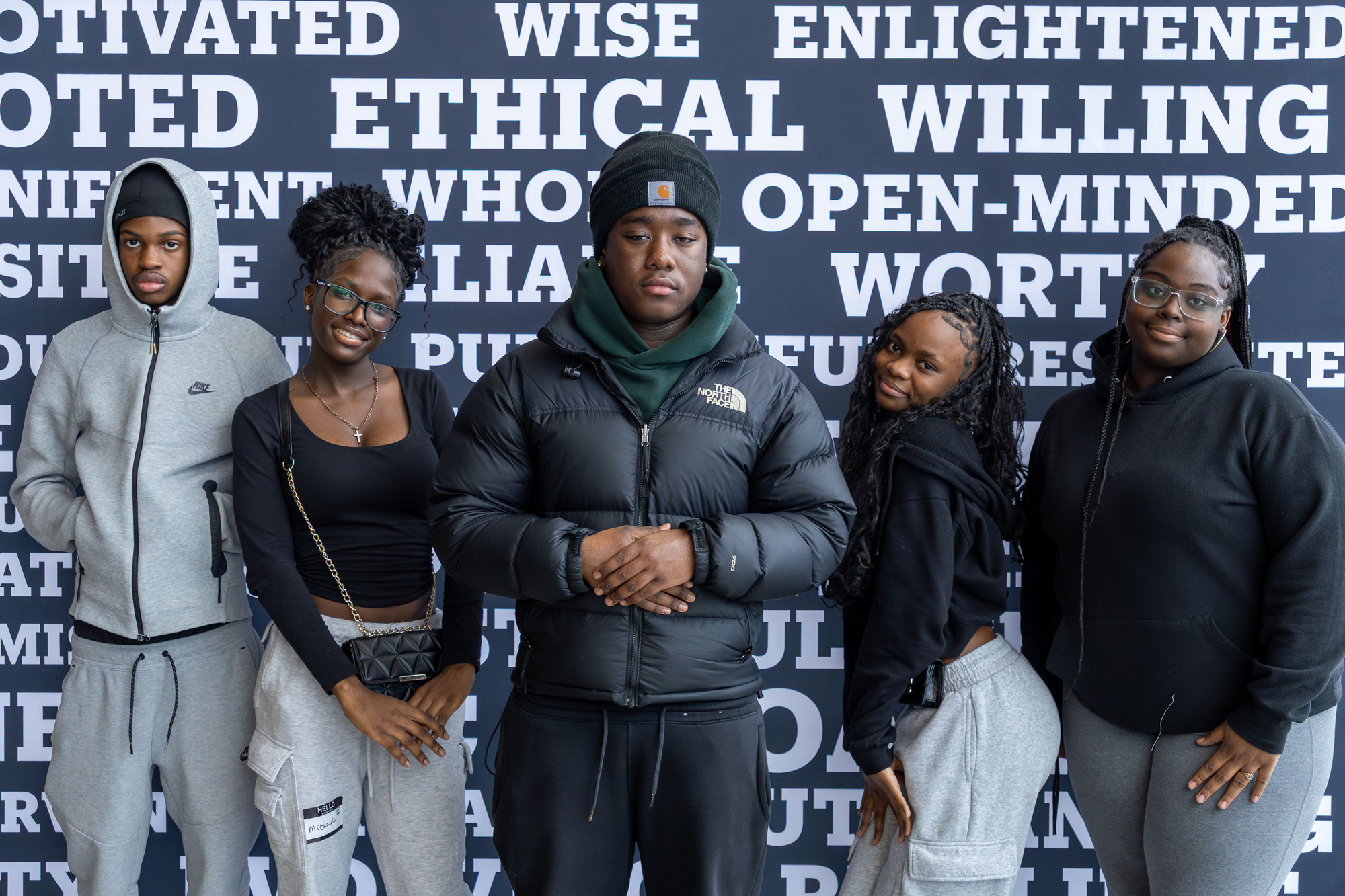 Participants at the Youth Empowerment Conference pose as a group in front of backdrop of inspiring words