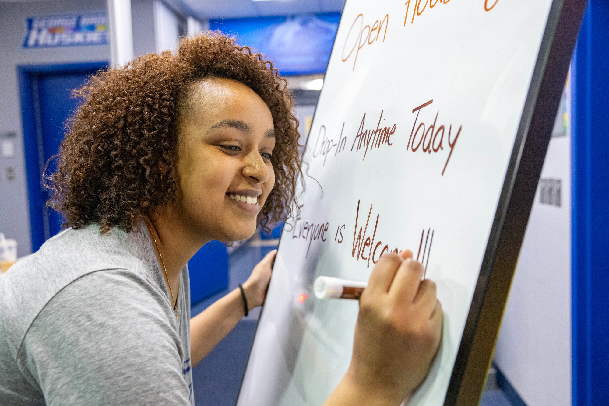 A student staff writes details on a whiteboard for guests at the spring open house