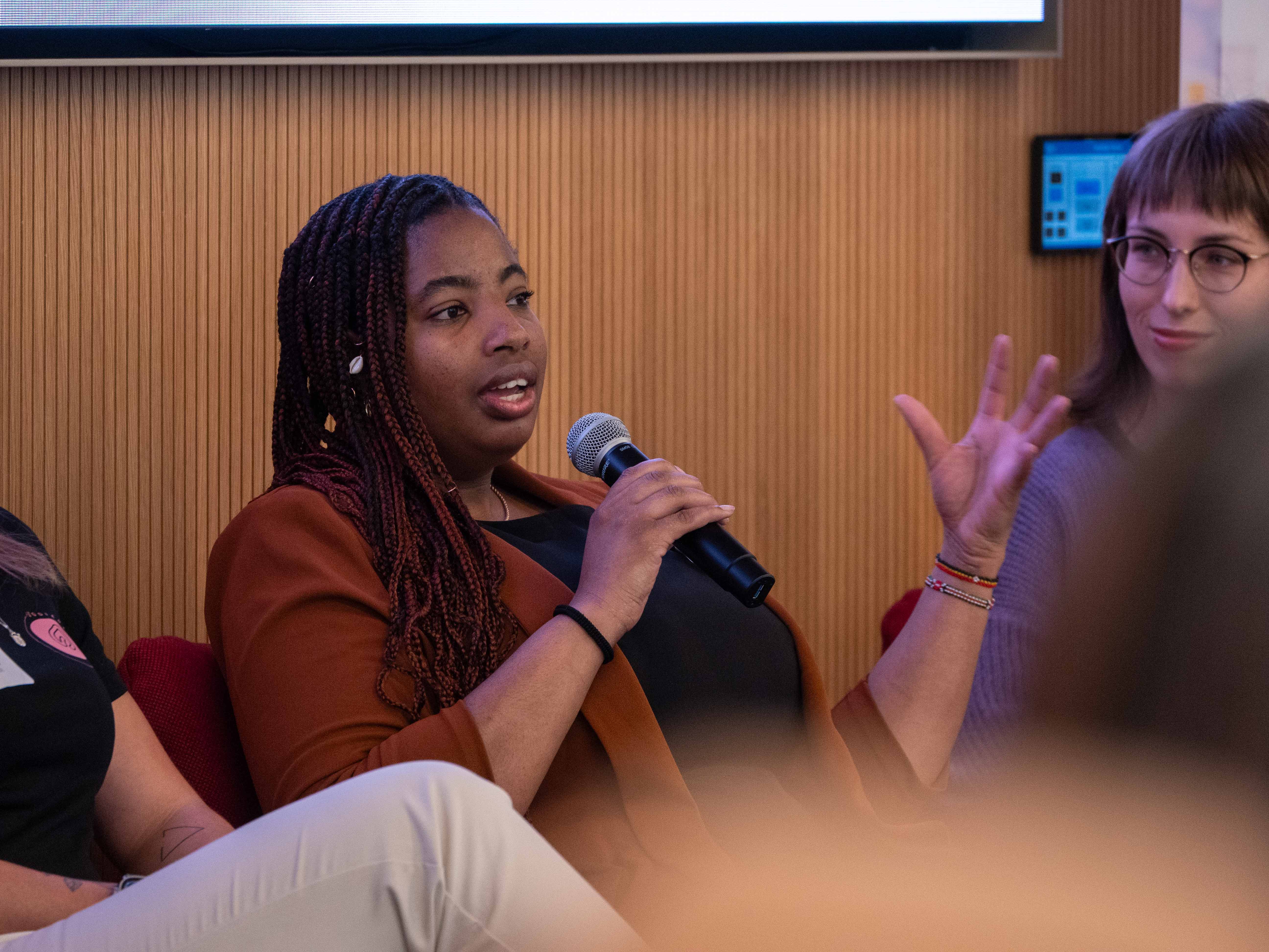 A woman with a microphone addresses an unseen audience