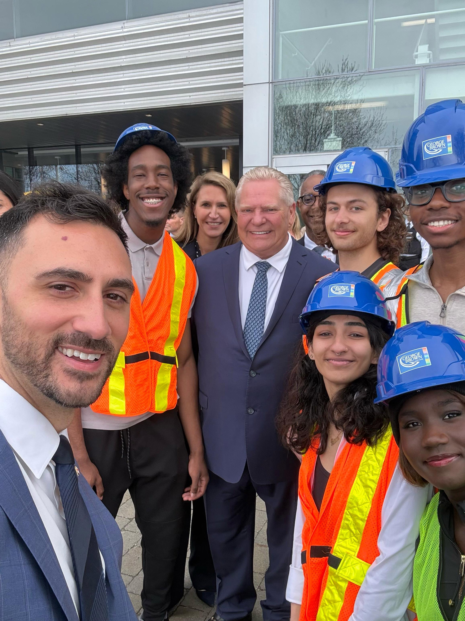 Minister Lecce takes a selfie with students in hard hats and vests with Premier Ford