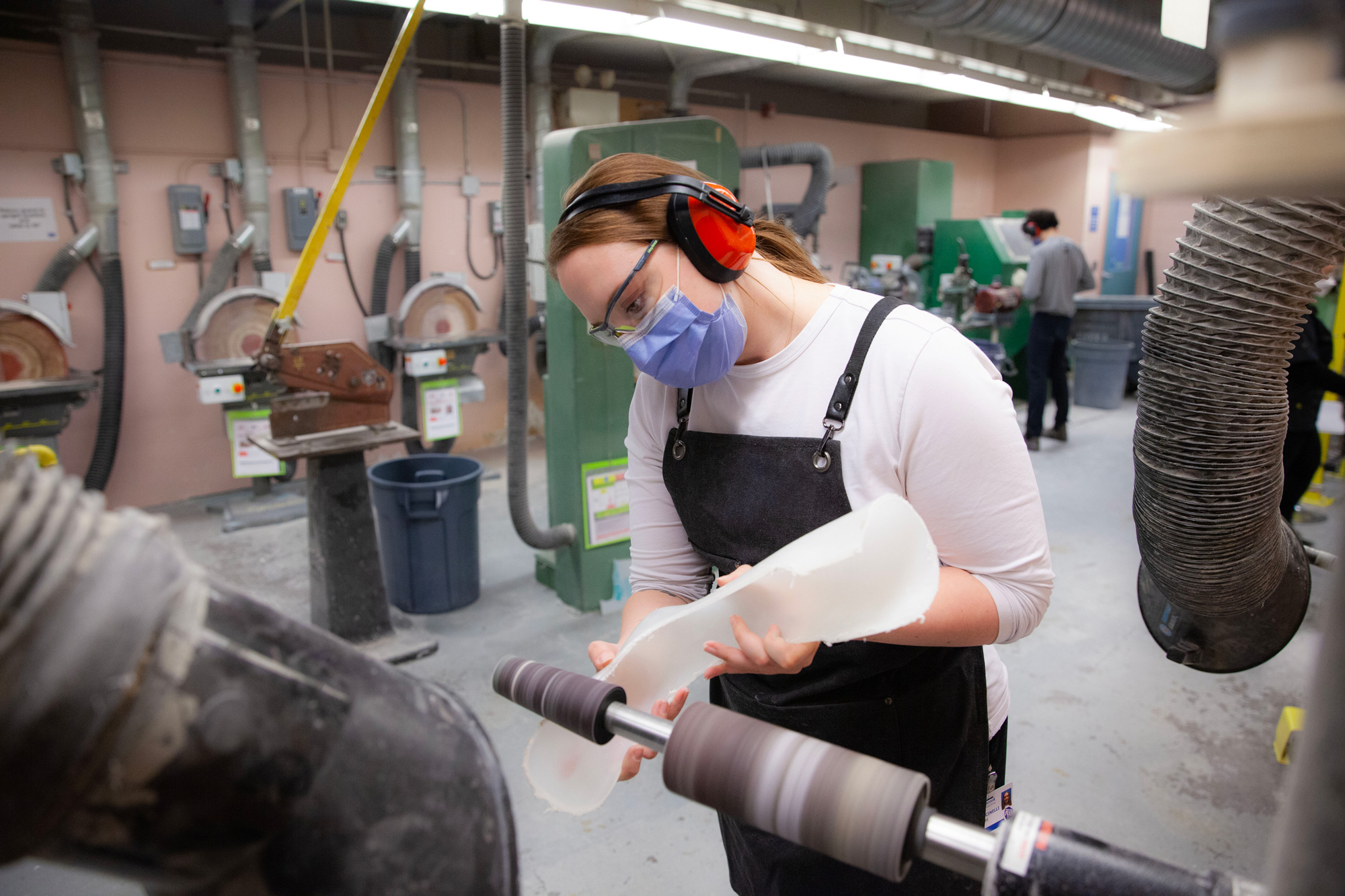 Student in George Brown Polytechnic Orthotic Prosthetic Technician program shaping a prosthetic device using a sanding machine in a lab.