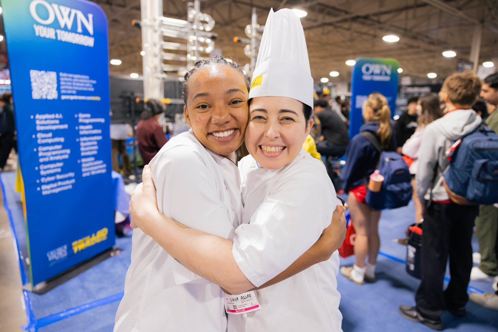 Chef Goday and Luca Assad hug at Skills Ontario