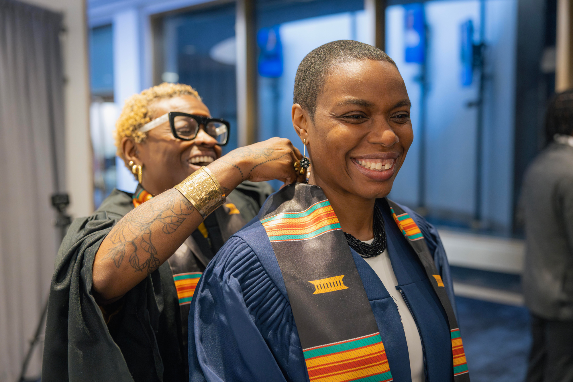 A graduating Black student has a Kente stole fitted on their gown at the Convocation ceremony.