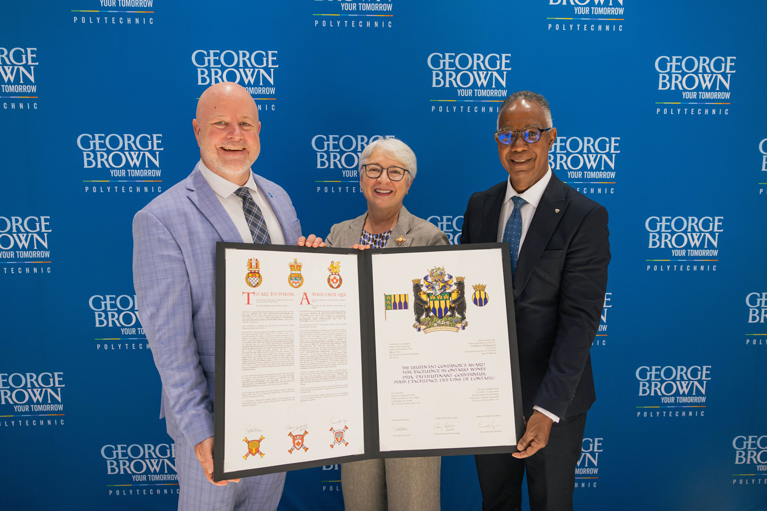 The Honourable Edith Dumont with Presidents Dr. Gervan Fearon and Sean Kennedy hold up the awards charter.