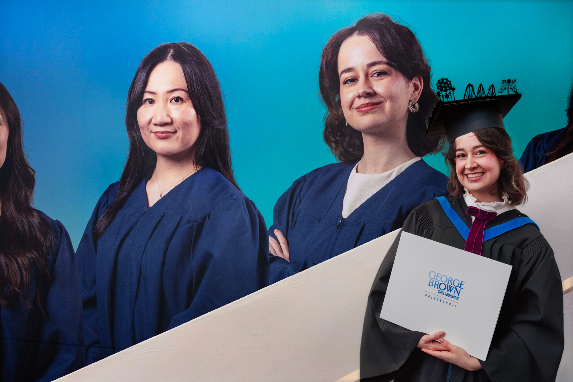Sara Vargas Nessi, the valedictorian for the School of Design, poses with the wall wrap that features.