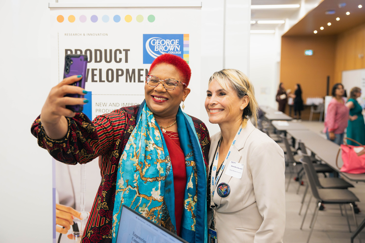 Guests at the RISE showcase take selfies together.