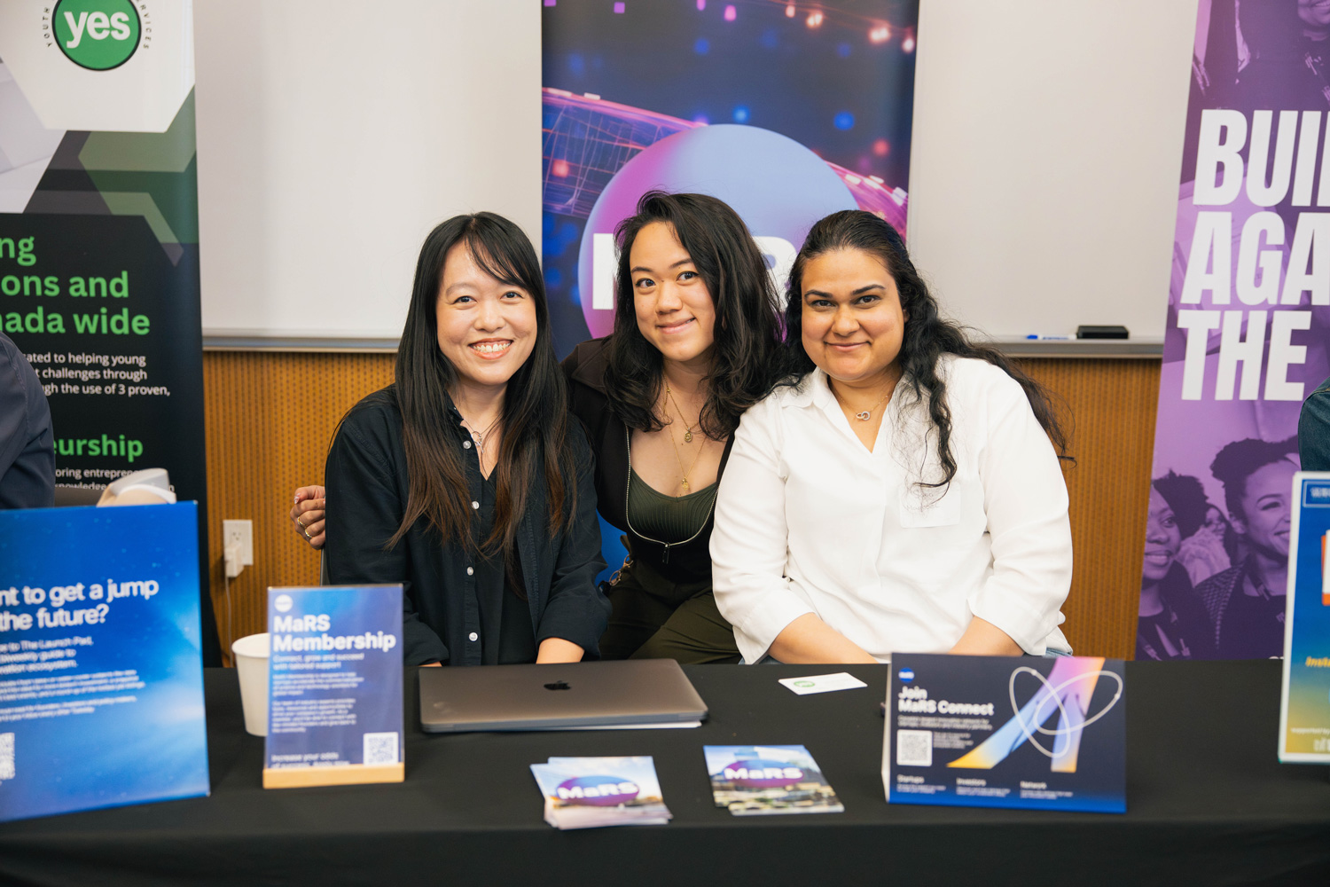 Three women table at the RISE entrepreneurship fair.